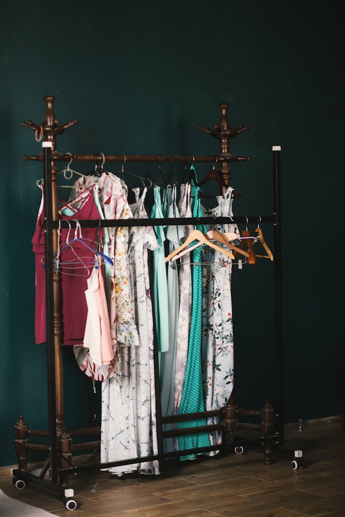 Home A stylish collection of dresses on a wooden clothes rack against a dark wall, creating a chic aesthetic.